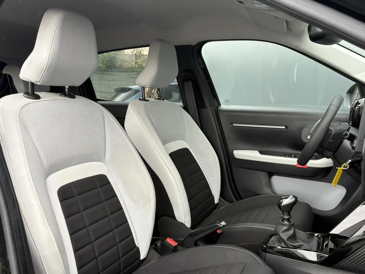 Vue intérieure côté gauche montrant les sièges bicolores gris clair et noir de la Citroën C3 Turbo 100 Max 2025.
