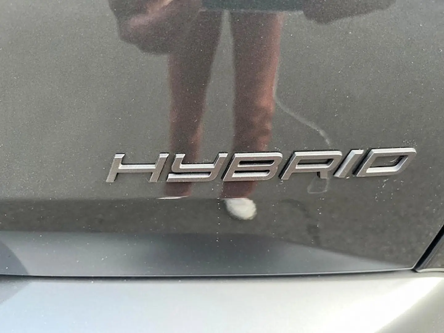 Gros plan sur l’inscription "HYBRID" en chrome sur la carrosserie gris titane d’un Peugeot 3008.