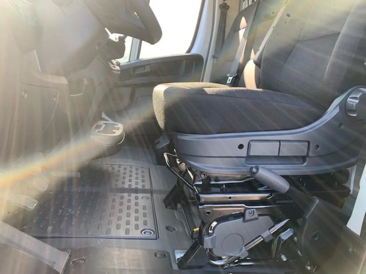 Siège conducteur noir avec accoudoir et levier de réglage, vue intérieure côté gauche du Fiat Ducato Fourgon blanc 2022.