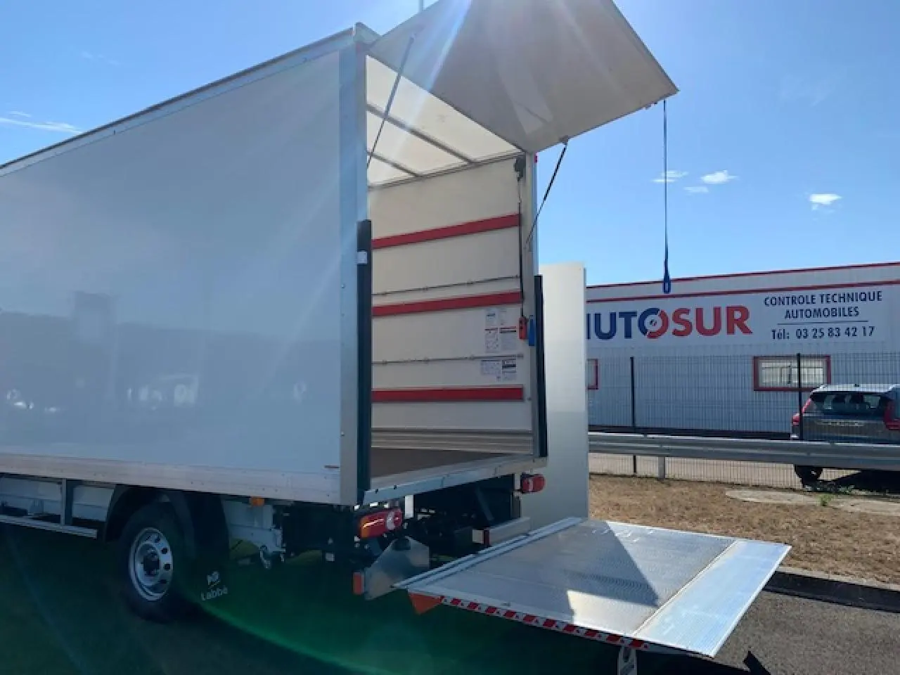 Vue arrière droite du FIAT Ducato blanc avec hayon élévateur déployé sous un ciel dégagé.