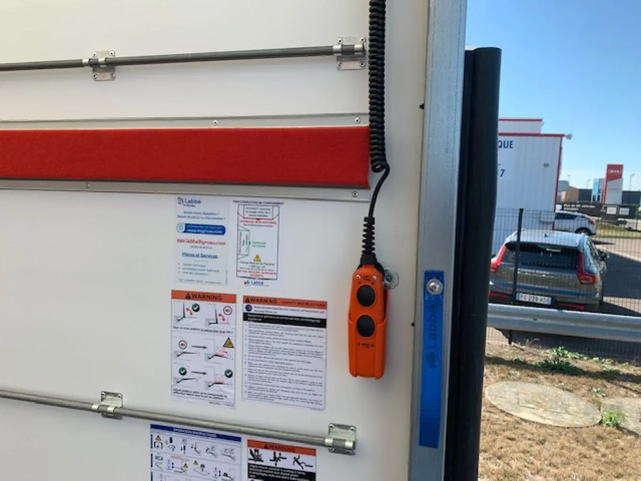 Vue arrière droite du FIAT Ducato Fourgon blanc 2022 avec hayon élévateur et commandes orange visibles.