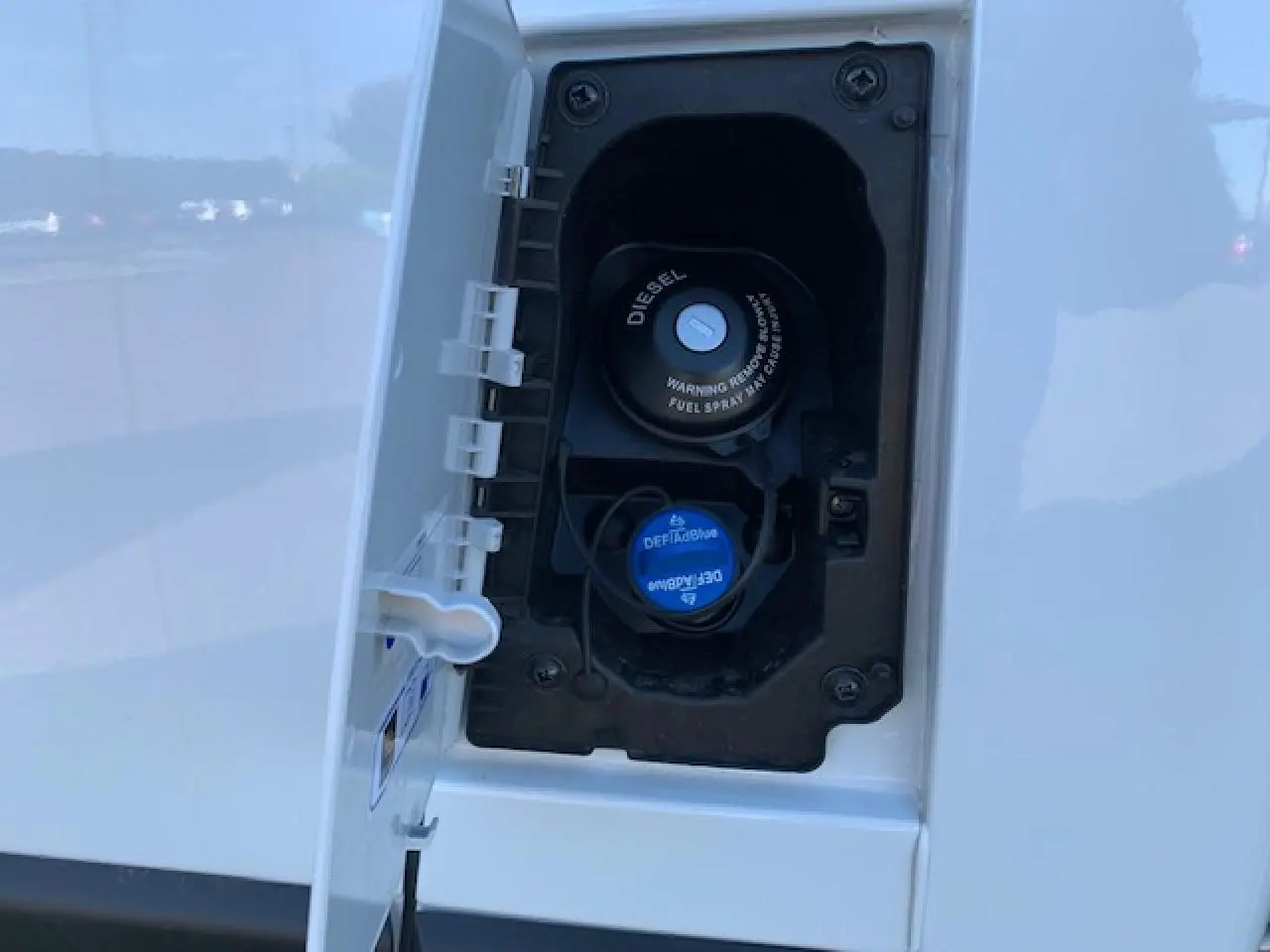 Gros plan sur la trappe à carburant diesel blanche du Fiat Ducato Fourgon 2022, avec bouchon DEF Blue bleu visible.