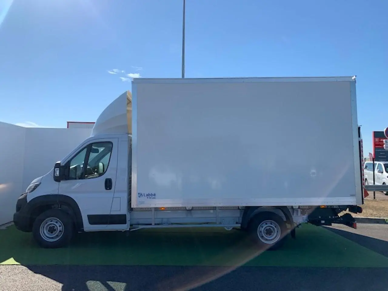 Fiat Ducato Fourgon blanc vu de profil côté gauche, avec caisse fourgon et hayon élévateur arrière.