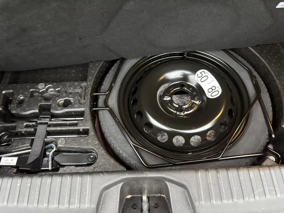 Coffre ouvert montrant la roue de secours et les outils de dépannage du Renault Clio V rouge flamme.