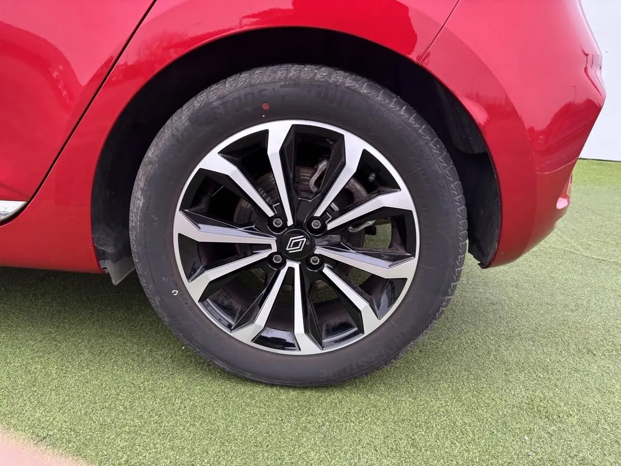 Gros plan sur la roue arrière droite de la Renault Clio V rouge flamme avec jante alliage noire et argentée.