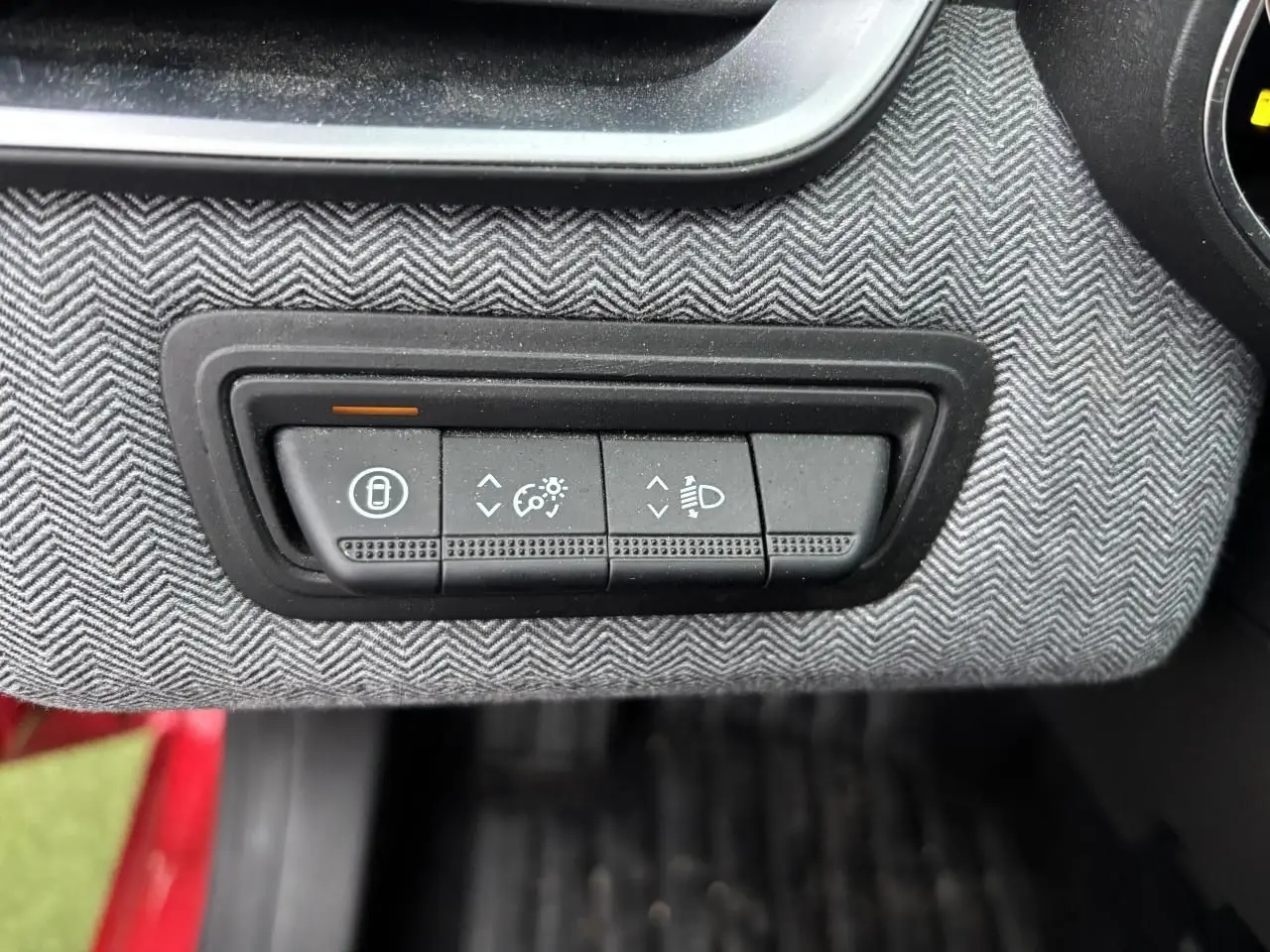 Gros plan sur les commandes d'éclairage et verrouillage sur la planche de bord gris chiné de la Renault Clio rouge flamme.