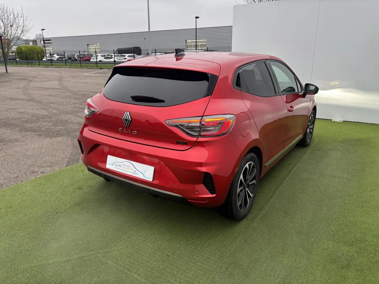 Renault Clio V rouge flamme métal vue 3/4 arrière droit, feux arrière LED et jantes alliage 16 pouces visibles.