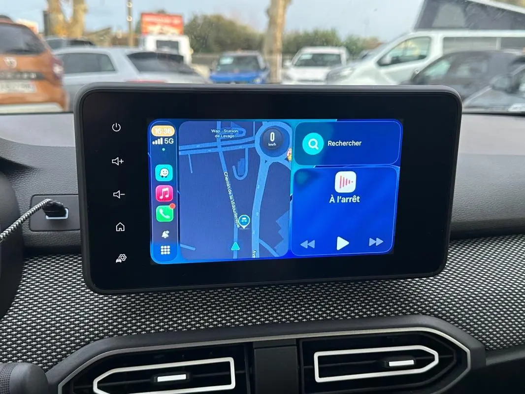 Écran tactile central du tableau de bord de la Dacia Sandero blanche, affichant un GPS en mode pause.