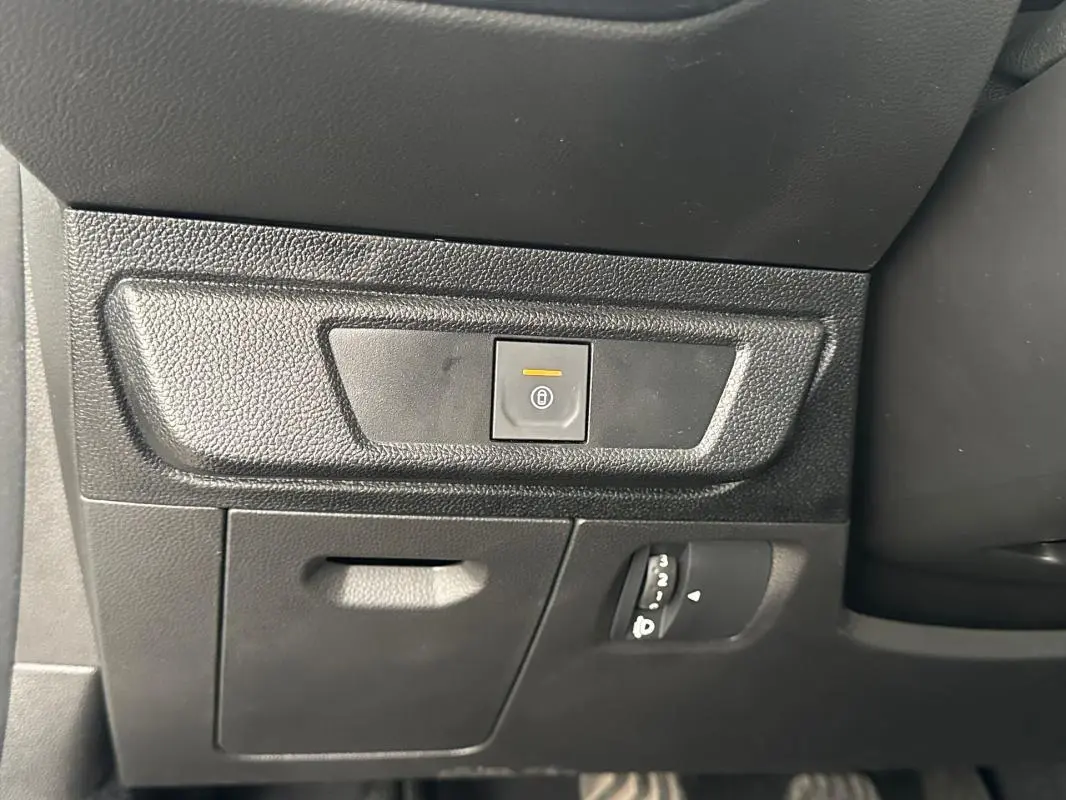 Détail du tableau de bord côté gauche de la Dacia Sandero blanche 2024, avec bouton de fermeture centralisée éclairé.