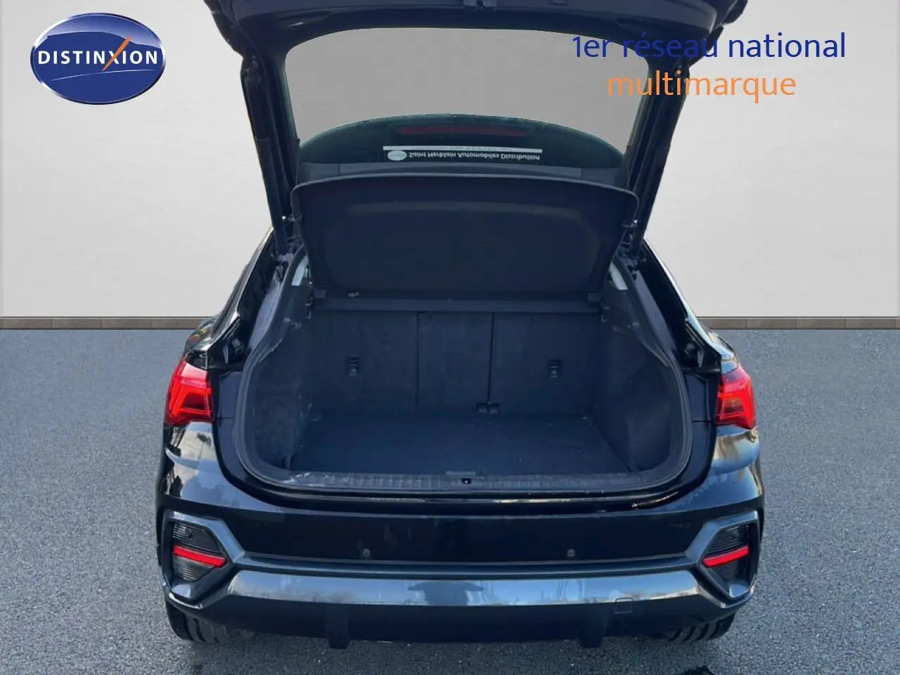 Vue arrière d’un Audi Q3 Sportback noir mythic avec coffre ouvert, mettant en valeur l’espace de chargement vide.