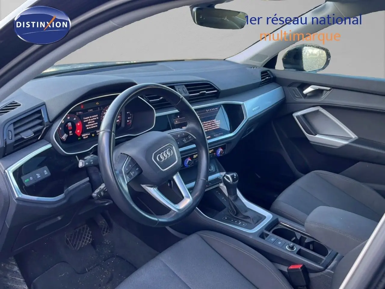Intérieur de l'Audi Q3 Sportback 2022 vu côté conducteur, tableau de bord moderne et sièges noirs.