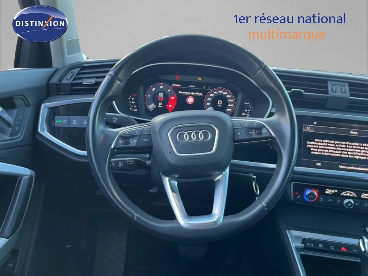 Vue intérieure centrée sur le volant Audi noir avec tableau de bord numérique et écran tactile du Q3 Sportback 2022.
