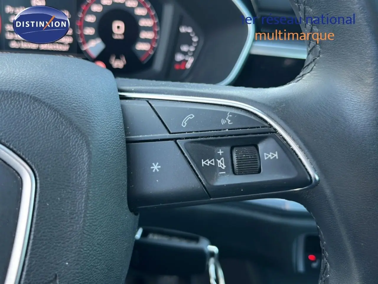 Gros plan sur les commandes multifonctions noires à droite du volant d’un Audi Q3 Sportback noir mythic, tableau de bord flou en arrière-plan.