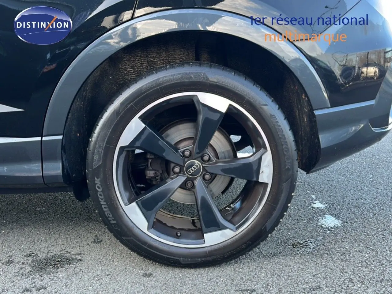 Gros plan sur la roue arrière droite d’un Audi Q3 Sportback noir mythic avec jante alliage bicolore.