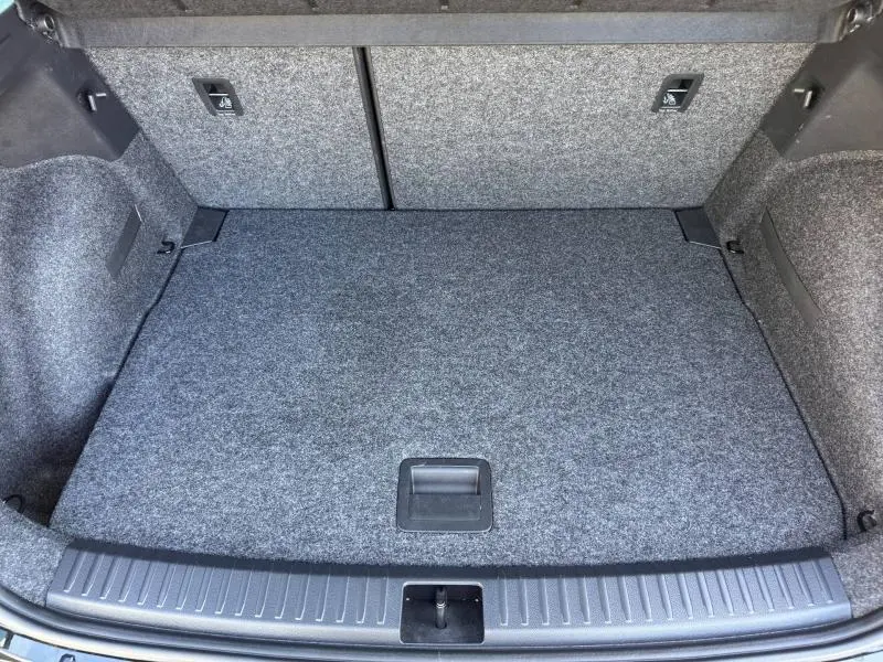 Coffre ouvert vu de face d'un SEAT Arona 2025, revêtement gris et compartiment de rangement plat.