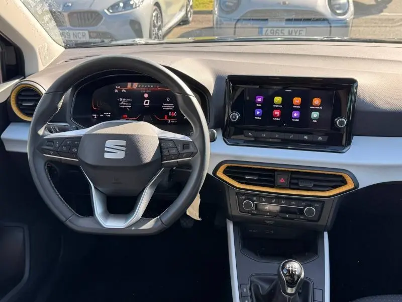 Vue intérieure avant du tableau de bord du SEAT Arona 2025, volant cuir multifonction et écran tactile central.