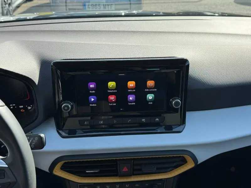 Vue intérieure du tableau de bord du SEAT Arona 2025, écran tactile central avec interface colorée.