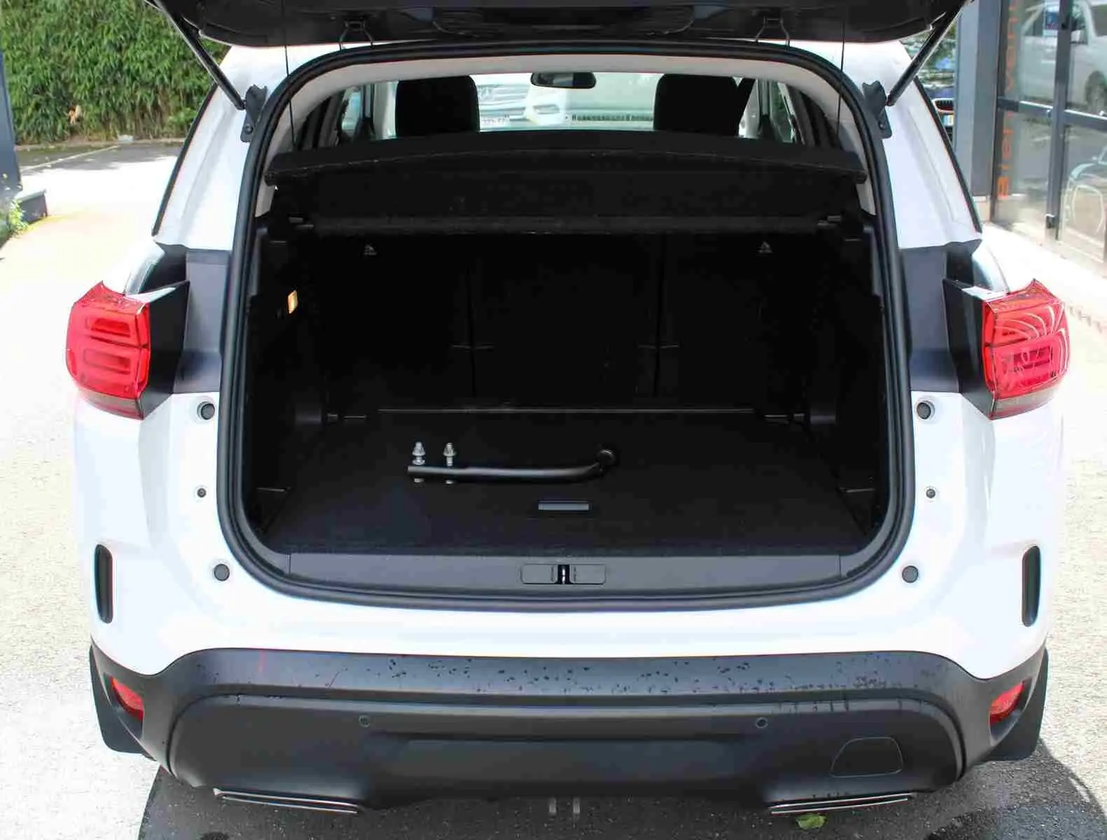 Vue arrière d’un Citroën C5 Aircross blanc 2020 avec coffre ouvert et attelage visible dans le coffre.