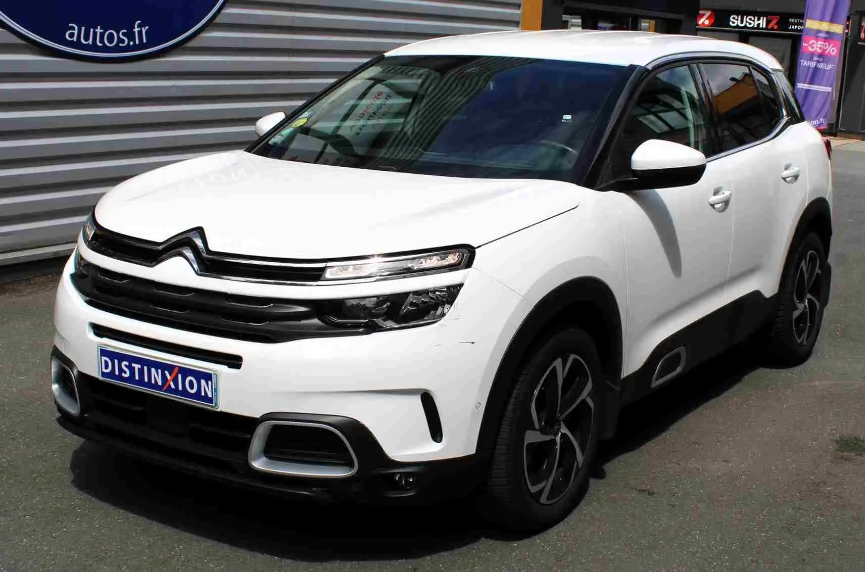 Vue 3/4 avant droit d'un Citroën C5 Aircross blanc avec jantes noires et détails de calandre noire.