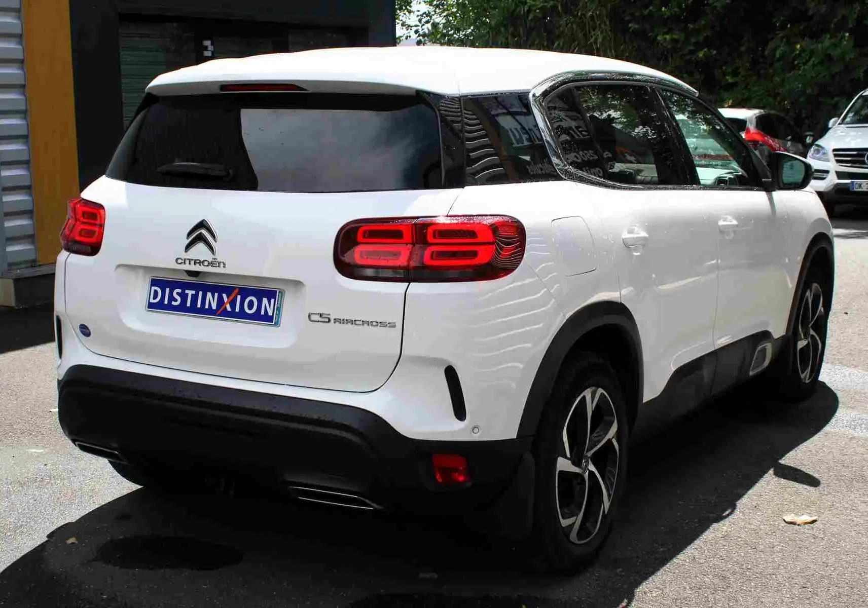Vue 3/4 arrière droite d'un Citroën C5 Aircross blanc avec feux arrière LED et attelage visible.