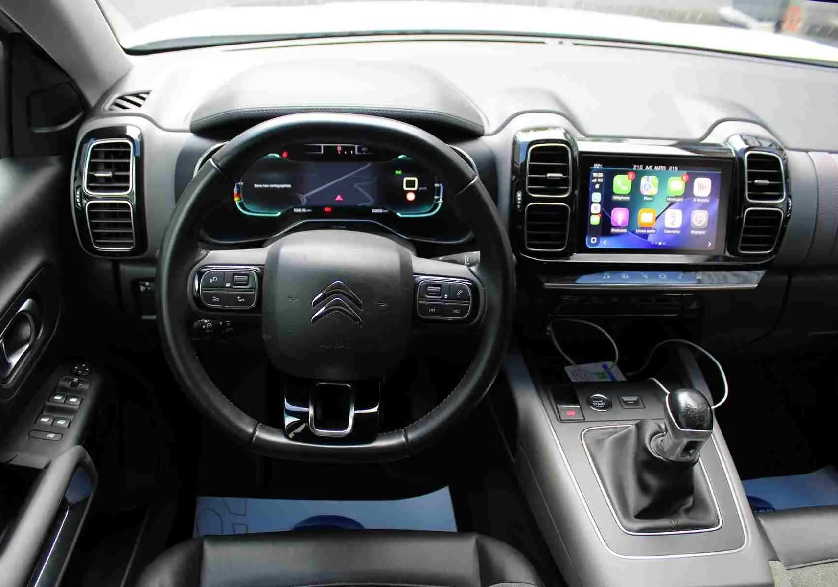 Vue intérieure centrée sur le tableau de bord et le volant du Citroën C5 Aircross avec écran tactile et levier de vitesse manuel.