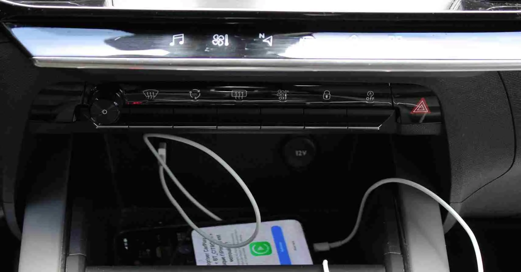 Gros plan sur la console centrale d'une Citroën C5 Aircross 2020, avec un smartphone blanc en charge via câble USB.