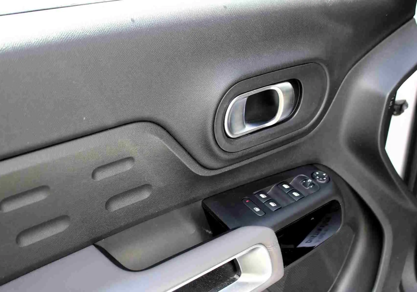 Détail de la porte intérieure côté conducteur du Citroën C5 Aircross blanc, avec commandes de vitres et poignée argentée.