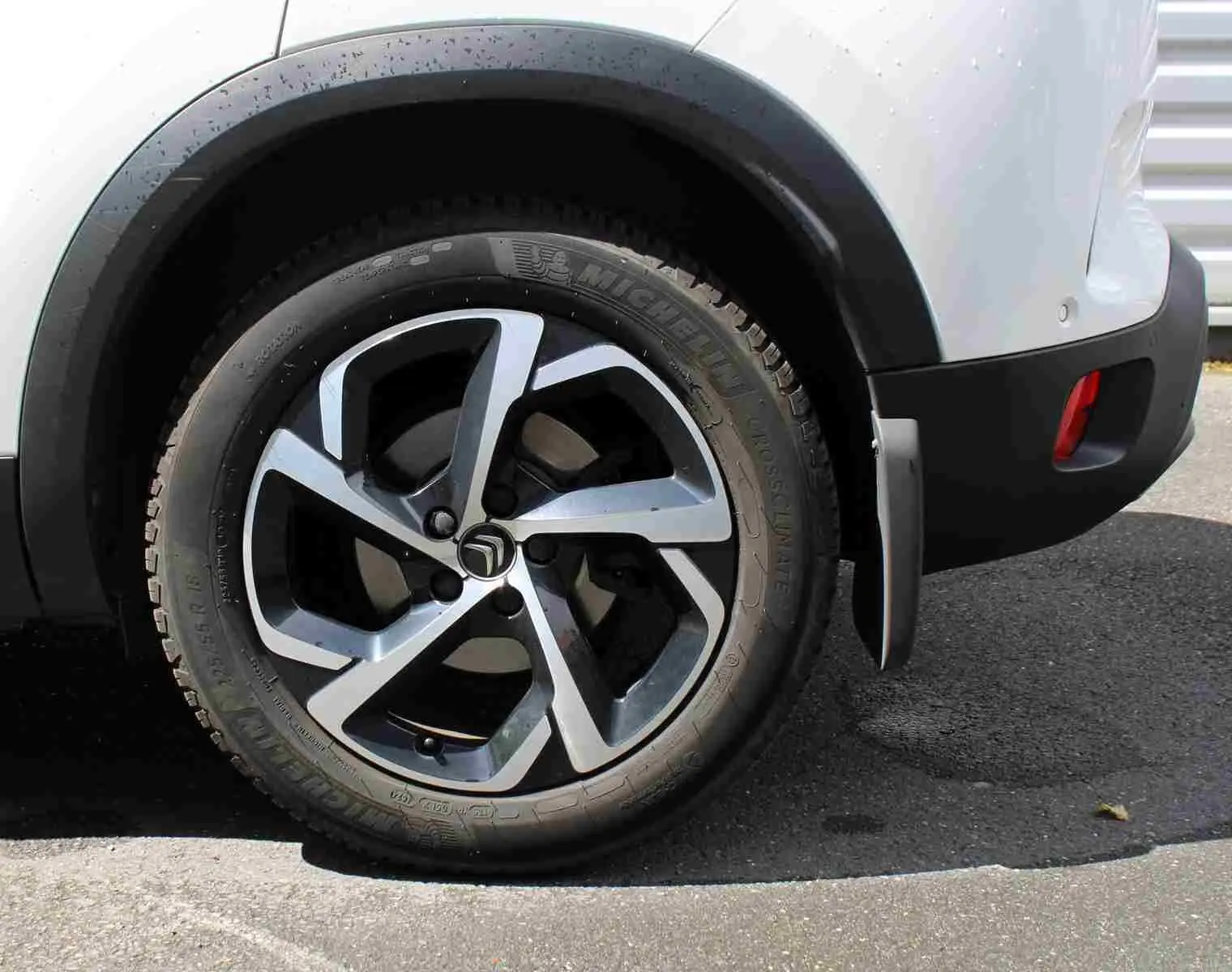 Gros plan sur la roue arrière droite d’un Citroën C5 Aircross blanc, avec jante alliage et pare-boue visible.