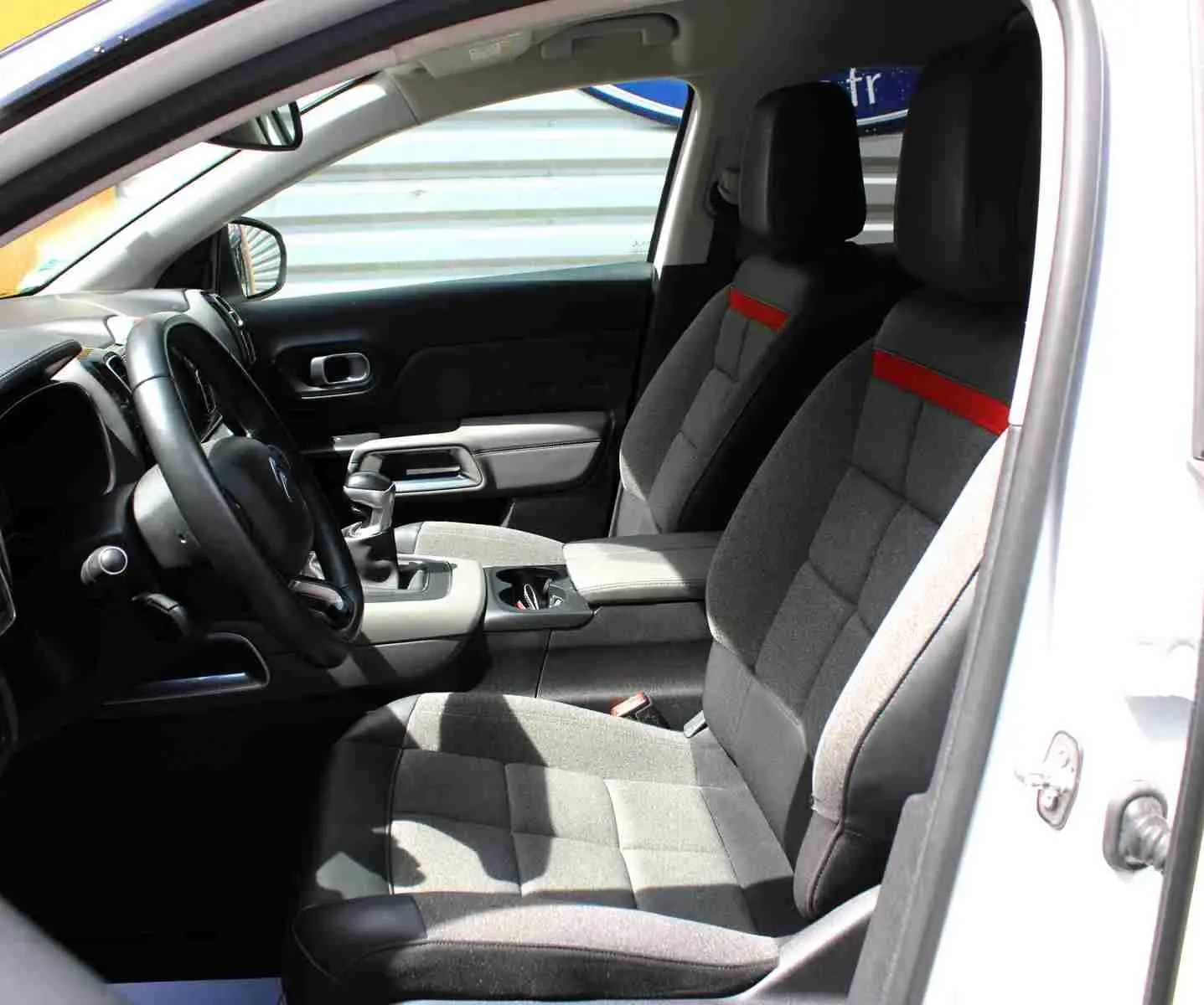 Vue intérieure côté conducteur du Citroën C5 Aircross blanc 2020, sièges tissu gris avec bande rouge et console centrale.