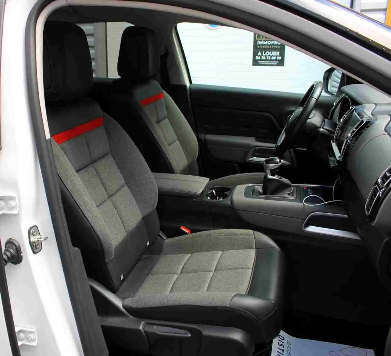 Vue intérieure côté gauche du Citroën C5 Aircross blanc 2020, sièges tissu gris avec bande rouge et console centrale noire.