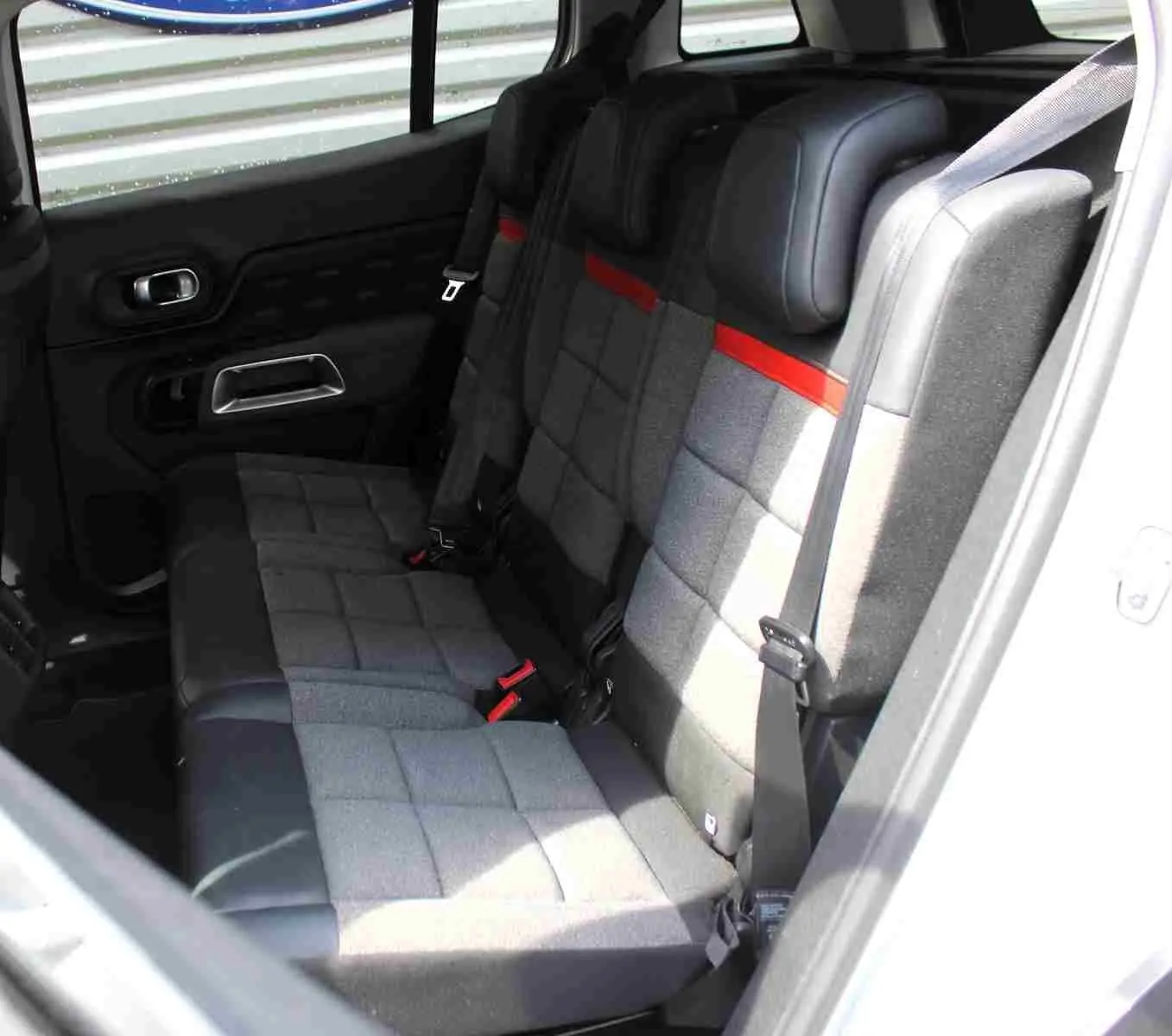 Vue intérieure côté droit montrant la banquette arrière grise avec surpiqûres rouges du Citroën C5 Aircross blanc.
