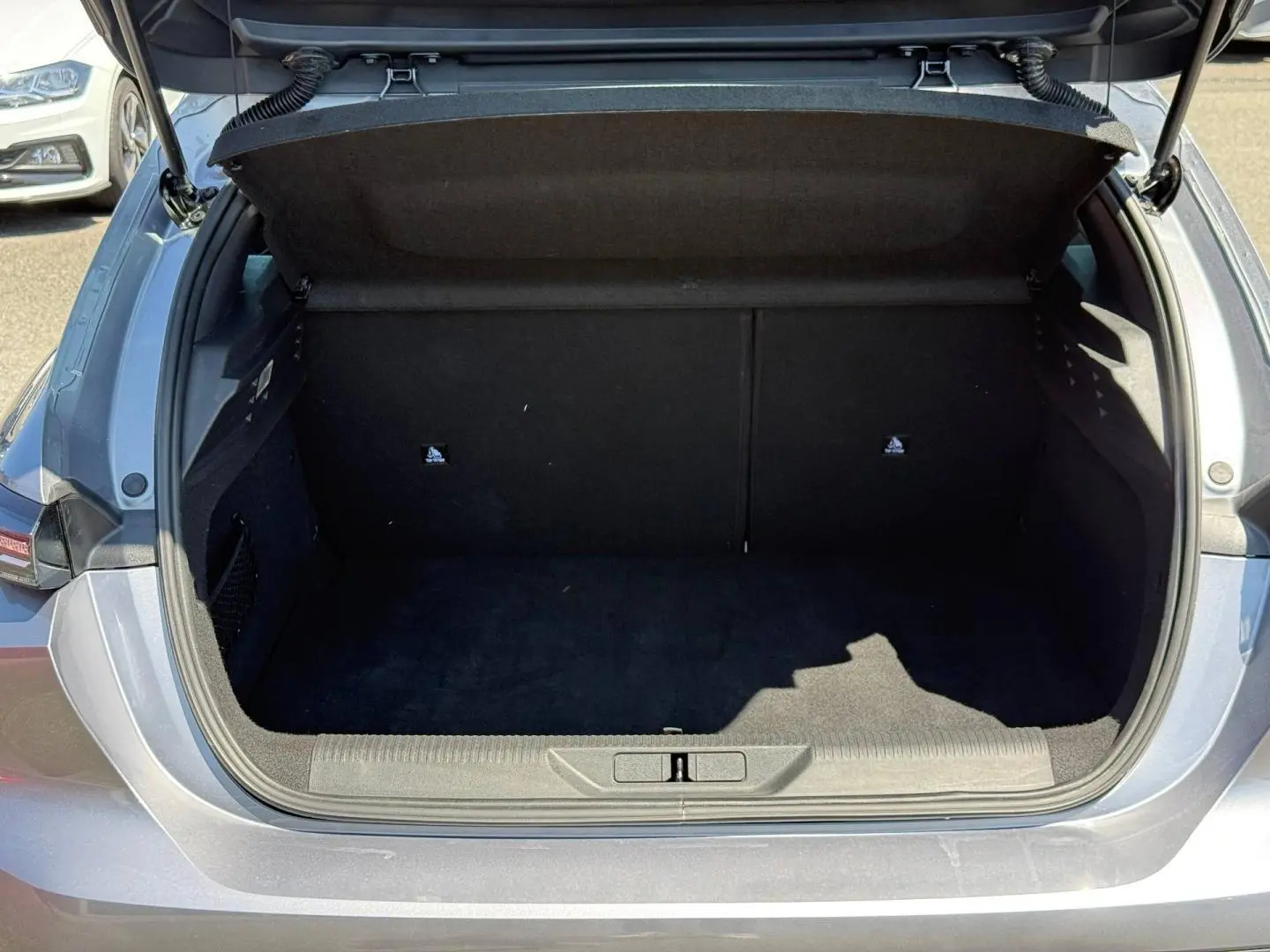 Coffre ouvert vu de l'arrière d'une Peugeot 308 e-308 gris Artense, montrant l'espace de rangement vide.