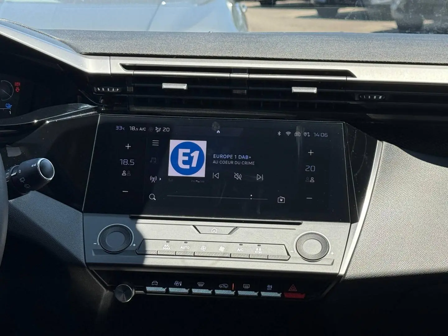 Vue rapprochée de la console centrale de la Peugeot e-308 2025 gris Artense, avec écran tactile et commandes climatisation.