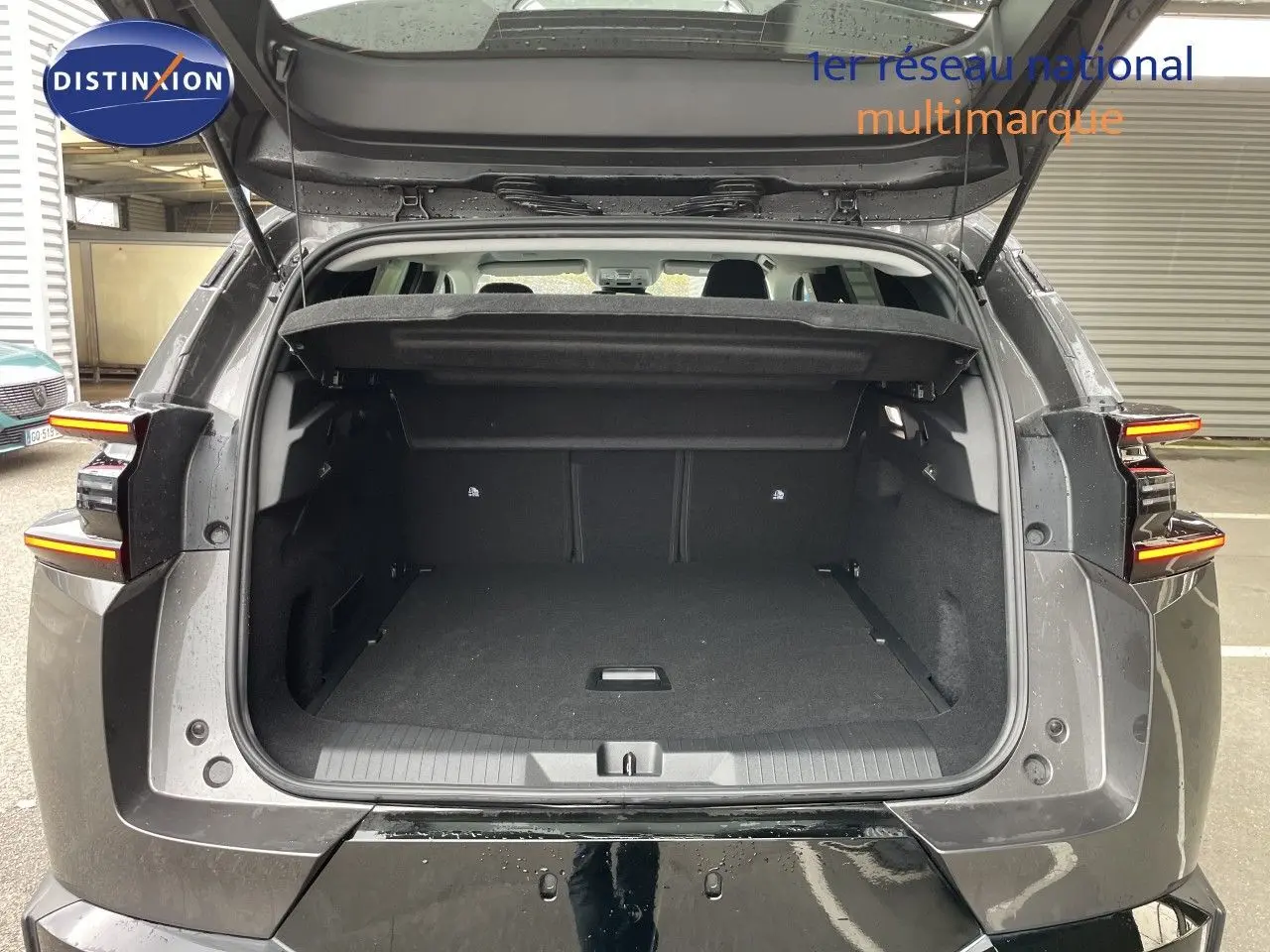 Coffre ouvert vu de l'arrière d'un Citroën C5 Aircross gris platinium métal avec feux arrière LED allumés.