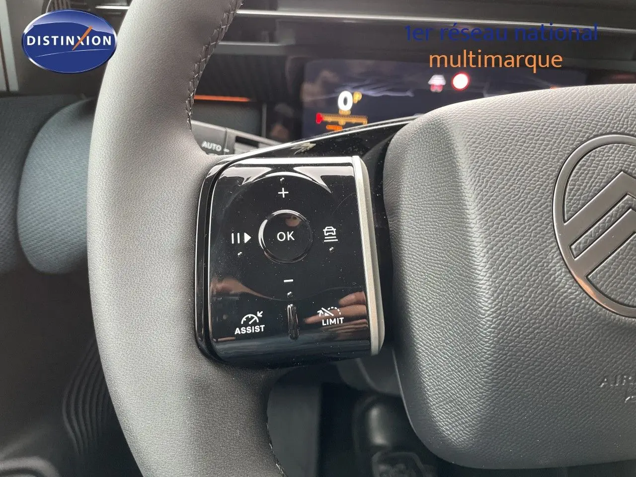 Gros plan sur le volant gris d’un Citroën C5 Aircross Hybrid 2026, avec commandes multifonctions et logo Citroën visible.