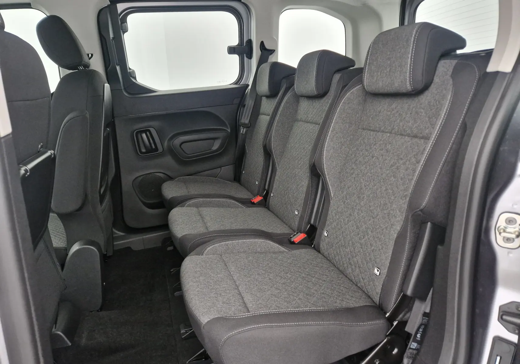 Vue latérale des trois sièges individuels arrière gris du Opel Combo Life Gris Artense avec habillage tissu et ceintures visibles.