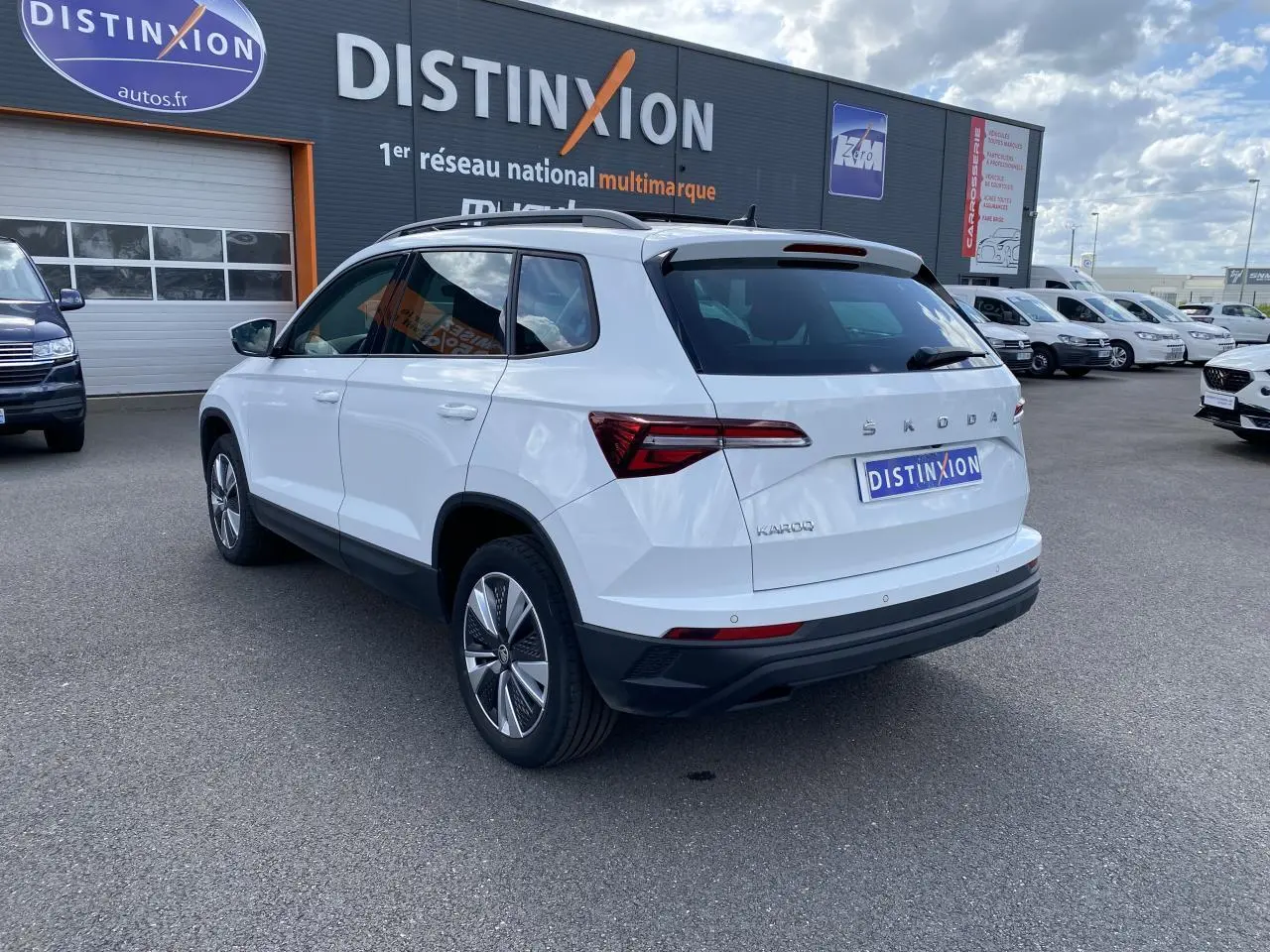 Vue 3/4 arrière droite d'un Skoda Karoq blanc moon métallisé avec jantes alliage et toit ouvrant panoramique.