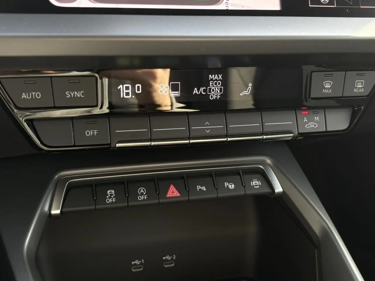 Gros plan sur la console centrale de l’Audi A3 Berline 30 TFSI 2024, affichage digital de la climatisation à 18°C.