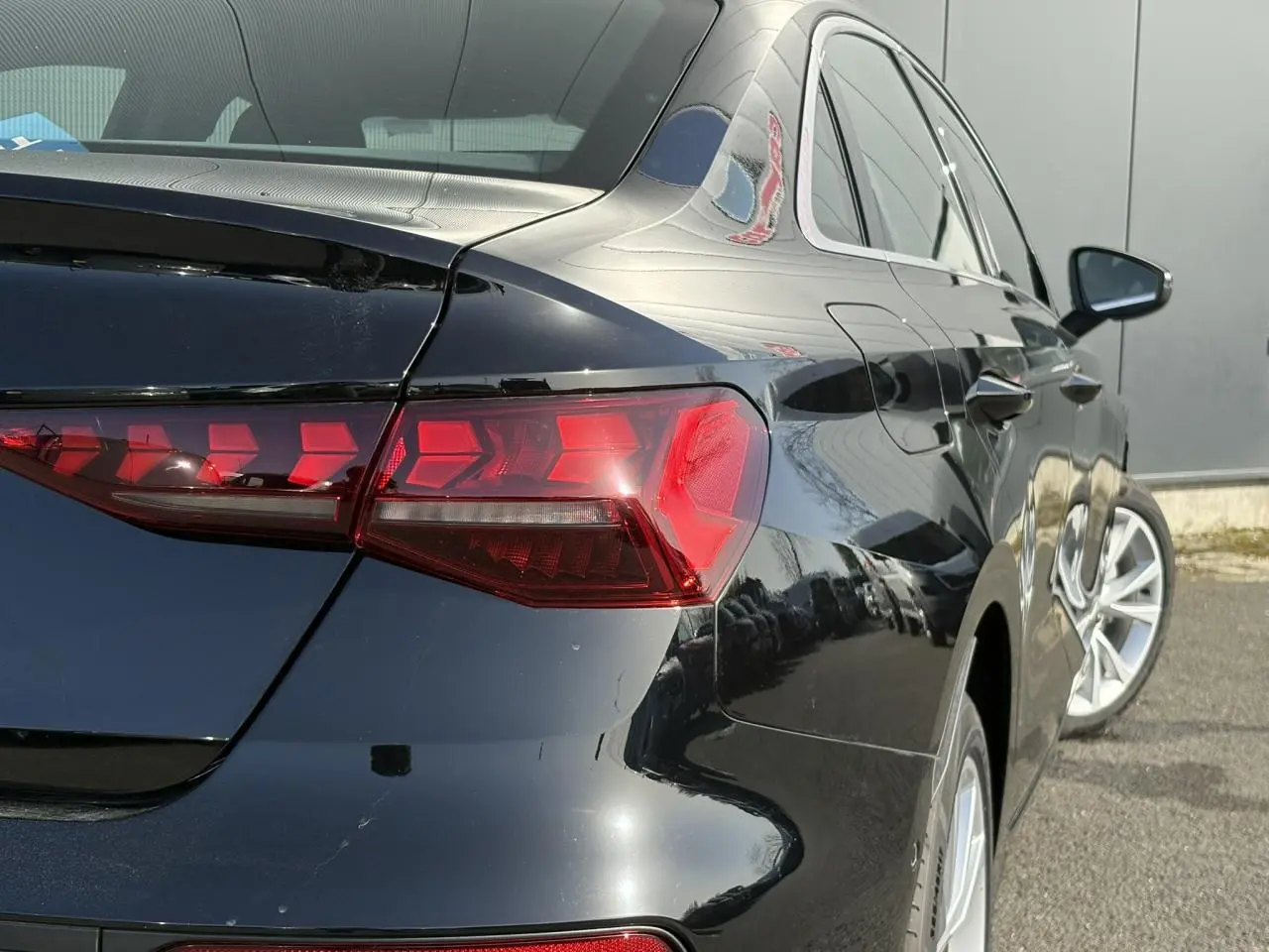 Vue 3/4 arrière droite de l'Audi A3 Berline 30 TFSI noir Mythe avec feux arrière LED distinctifs et jantes 17 pouces.