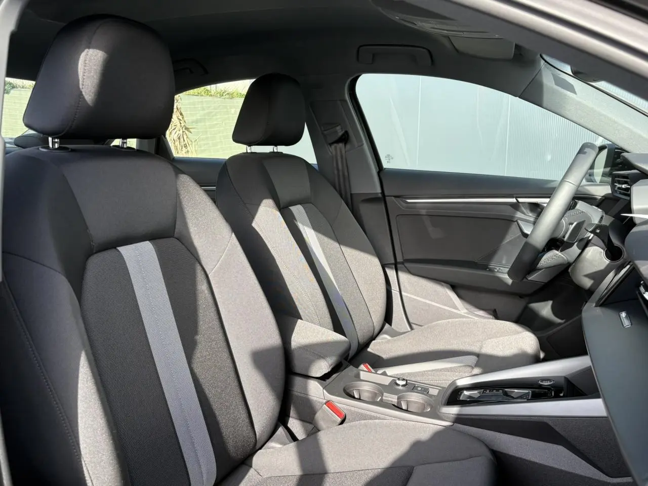 Vue intérieure côté droit de l’Audi A3 Berline 30 TFSI 116 S-tronic Advanced Edition avec sièges tissu gris et console centrale.