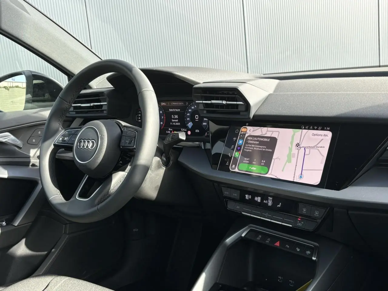 Vue intérieure côté conducteur de l'Audi A3 Berline 30 TFSI 2024, tableau de bord avec écran tactile et volant cuir noir.