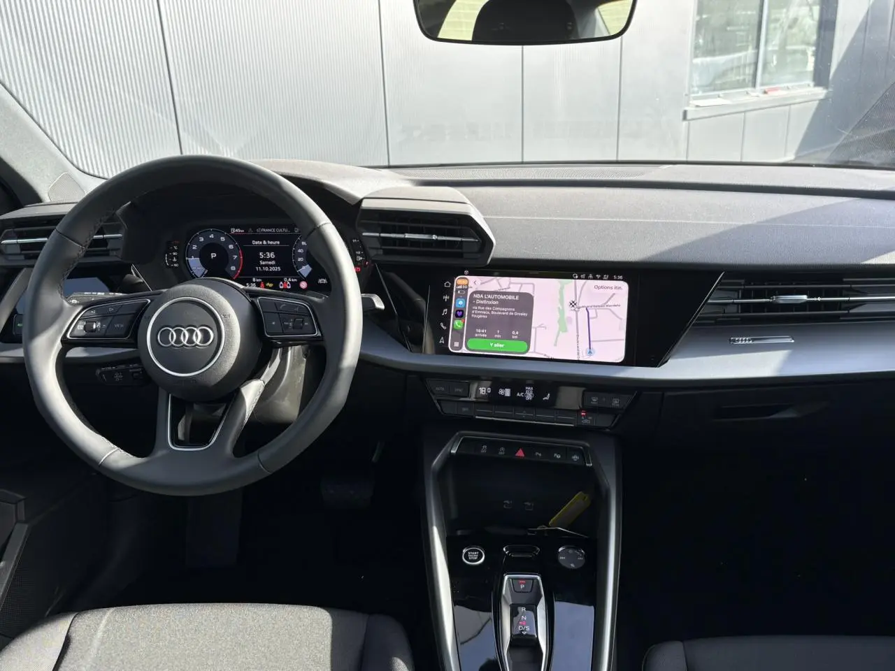 Vue intérieure avant de l'Audi A3 Berline 2024 noir Mythe, avec tableau de bord digital et écran central tactile.
