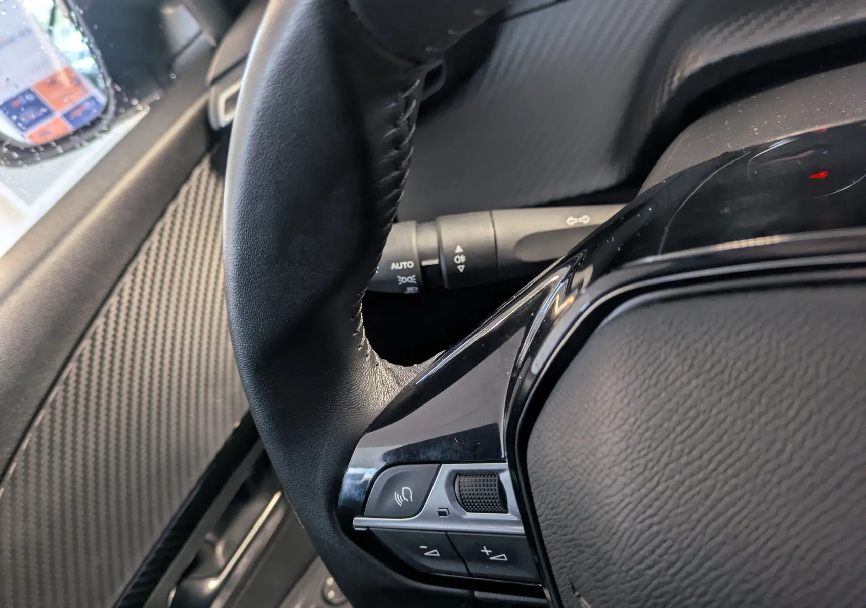 Gros plan sur le volant cuir noir de la Peugeot 208 PureTech 100 S&S BVM6 Active, avec commandes intégrées.