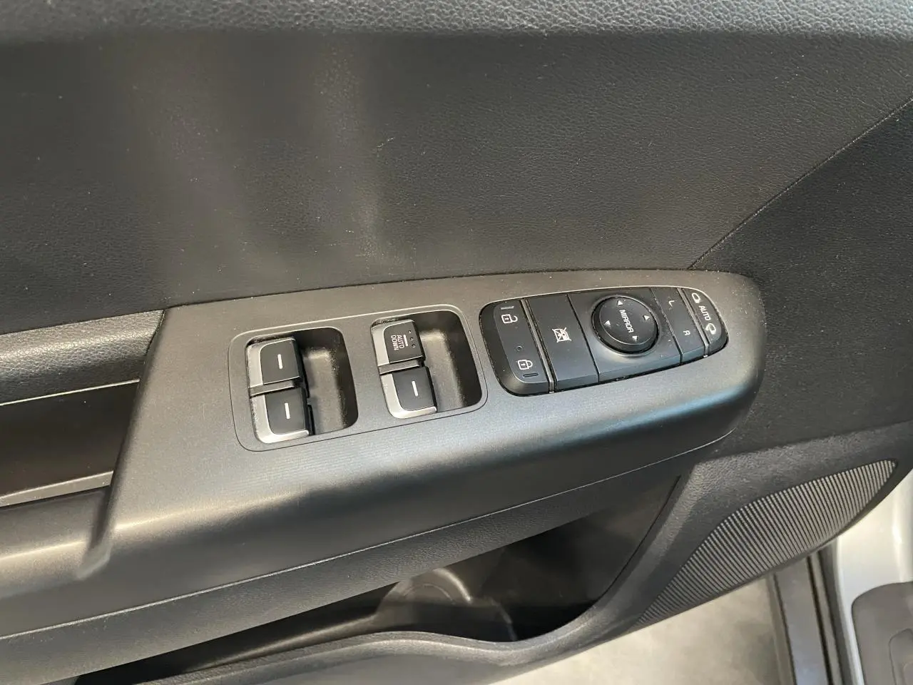 Vue rapprochée des commandes de lève-vitres et rétroviseurs sur la porte côté conducteur du KIA Sportage gris clair 2021.