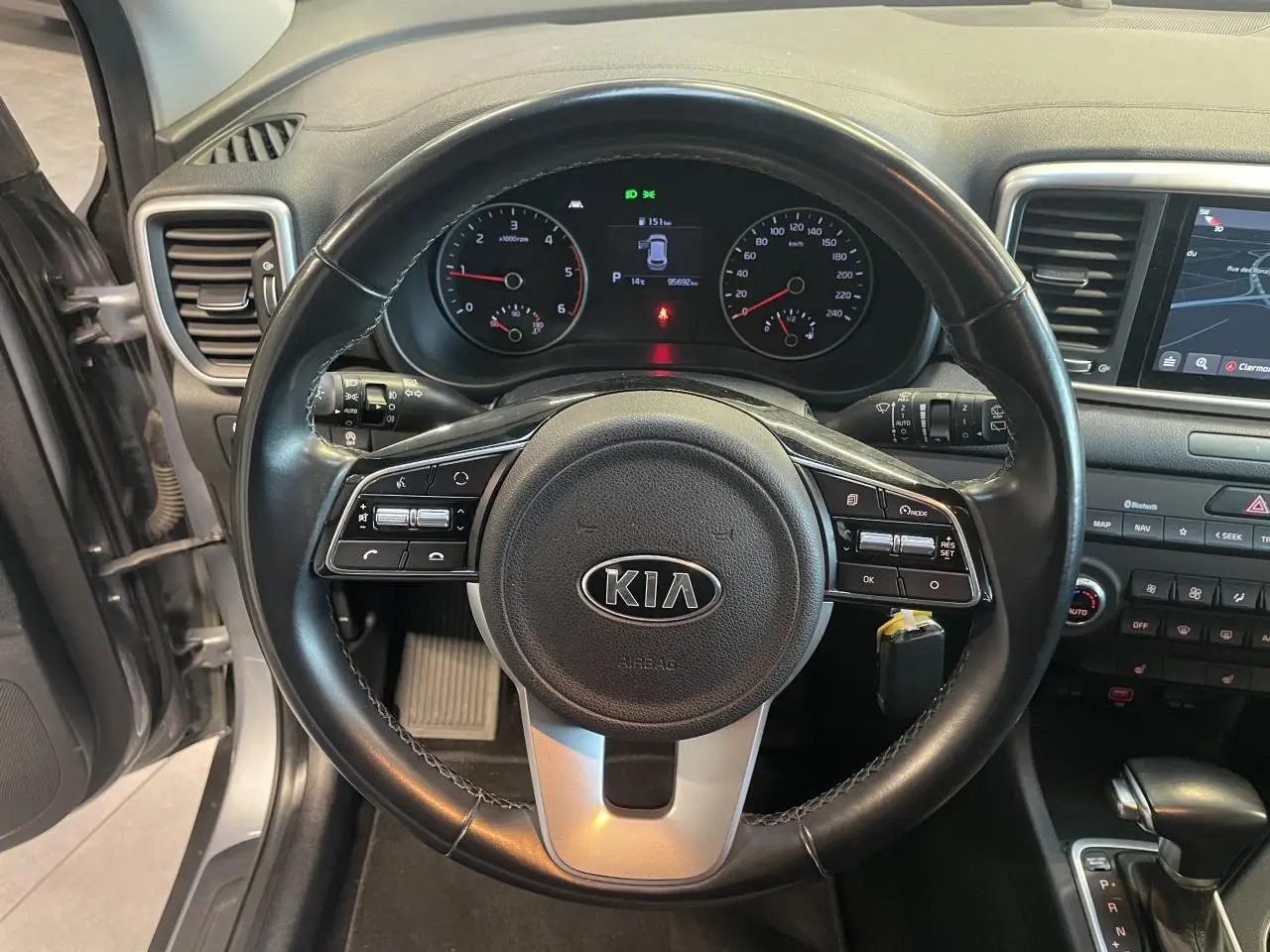 Vue intérieure centrée sur le volant noir du Kia Sportage 2021 avec tableau de bord et écran tactile visibles.