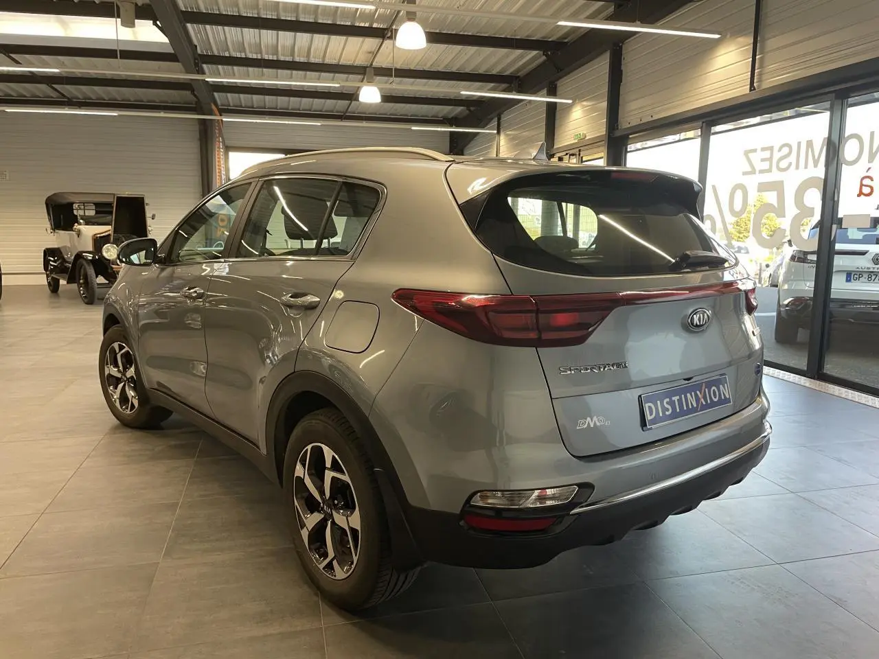 Vue 3/4 arrière droite du KIA Sportage gris clair 2021 avec jantes alliage et becquet arrière intégré.