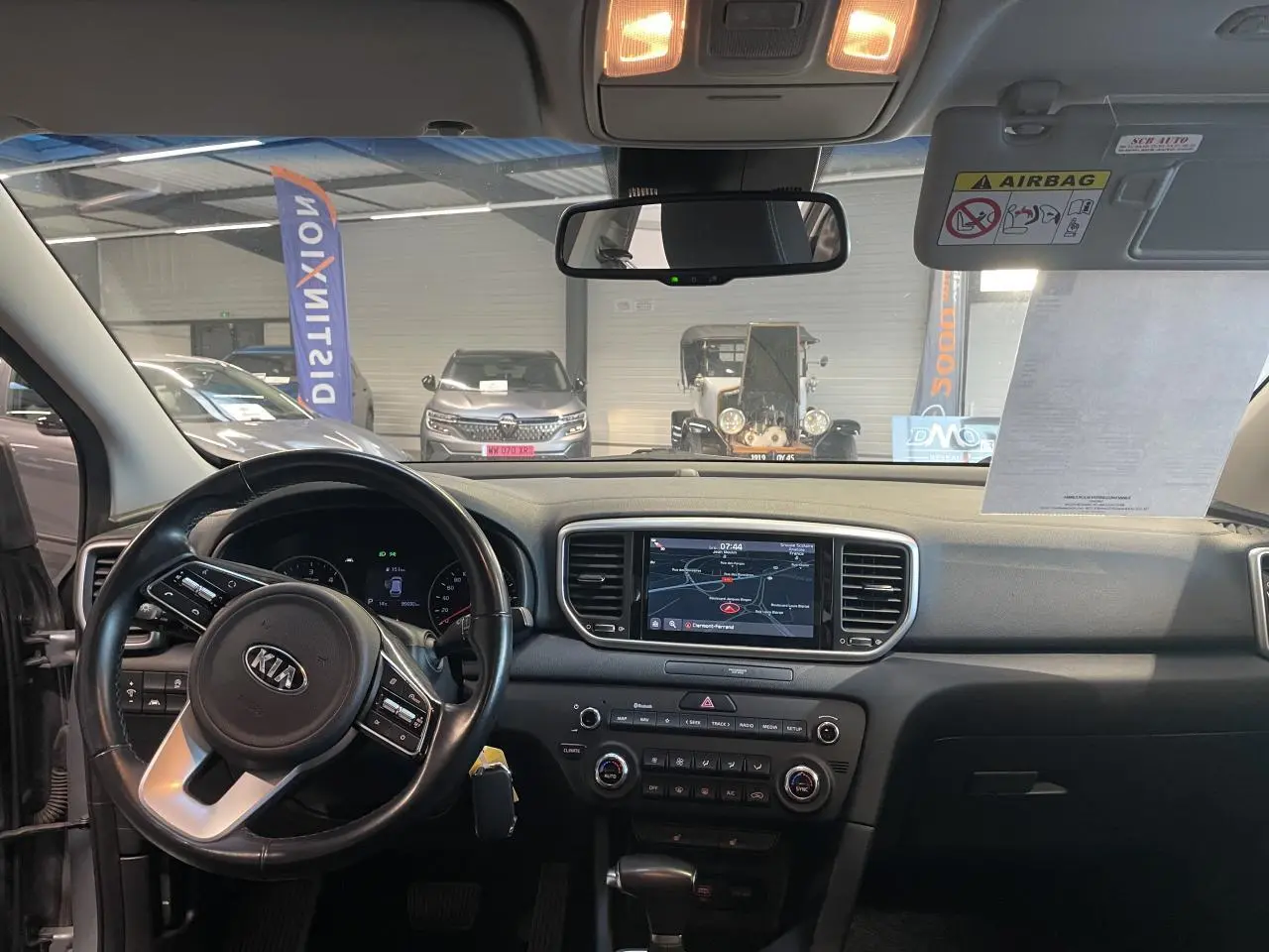 Vue intérieure avant du Kia Sportage 2021, tableau de bord noir avec écran tactile et volant multifonctions.