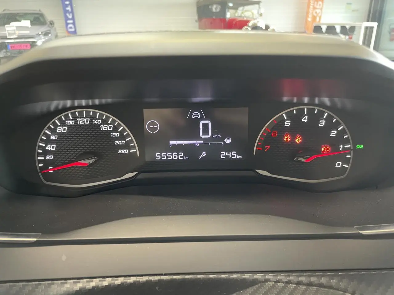 Vue rapprochée du tableau de bord numérique et analogique de la Peugeot 208 gris Artense, affichant 55562 km.