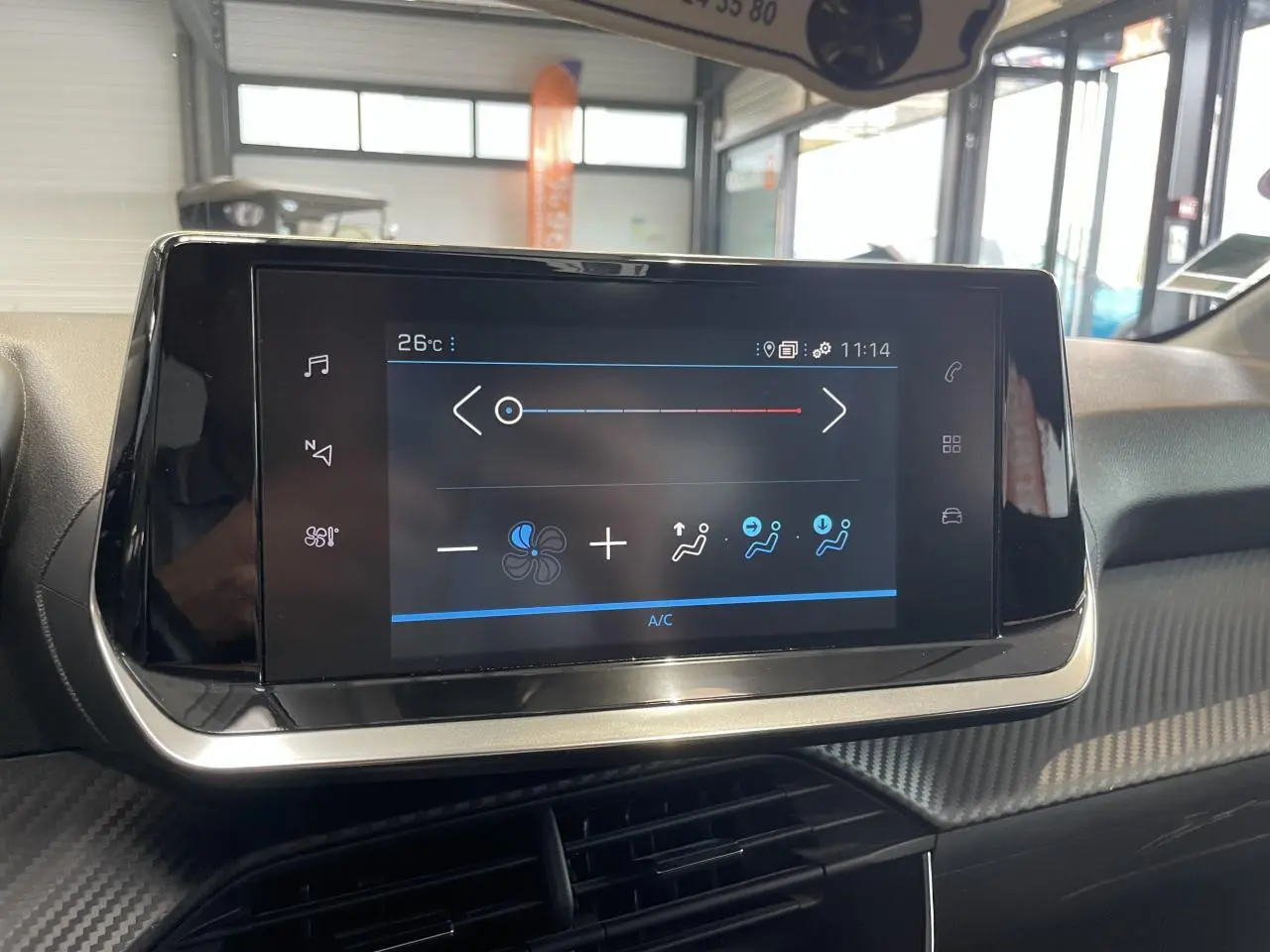 Écran tactile central de la climatisation sur tableau de bord avec décor carbone dans Peugeot 208 gris Artense.
