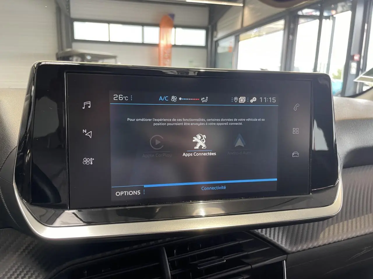 Écran tactile central du tableau de bord Peugeot 208 2021, avec interface connectée et finition carbone.